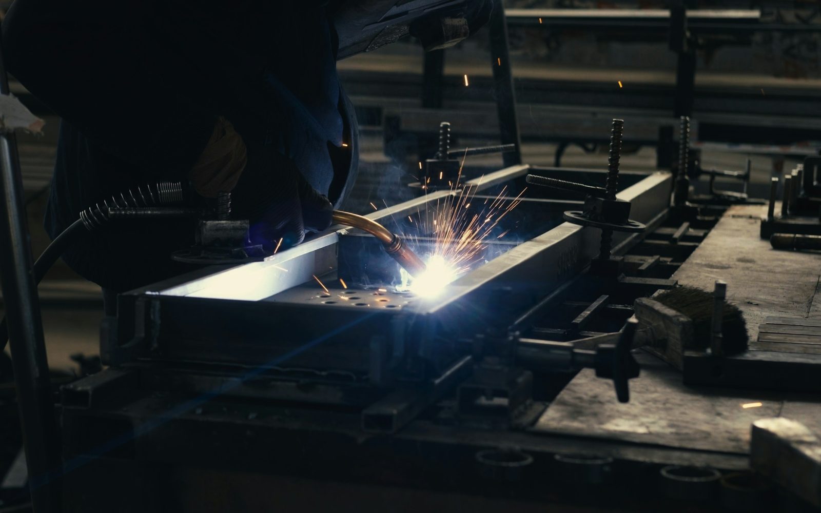 Qualified welder joining a steel fabrication assembly in a workshop.